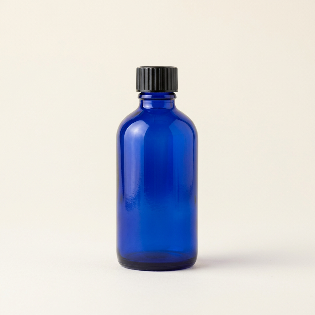 100 mL blue glass pharmacy bottle with black cap on an off-white background